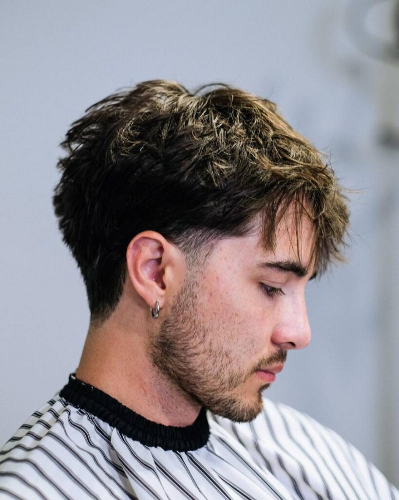 Front-facing view of a blowout taper haircut, with richly constructed waves on top transitioning into a flawlessly executed taper fade, offering a modern and stylish contour to the facial frame.